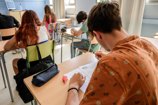 rear view of a male high school student writing a test in the classroom